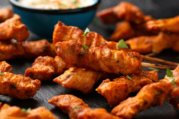 Grilled chicken fillet on skewers with white sauce on rustic stone board