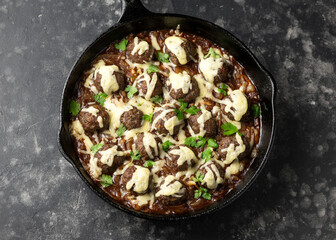 French onion beef meatballs in iron cast pan.