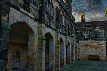 Fototapeta na wymiar Historic stone building with archways under a dramatic sky at dusk in Lancaster.