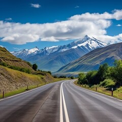 Fototapeta premium Beautiful mountain road landscape with snow capped mountains in distance,
