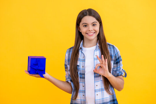 teen girl shopping with present in studio, ok. teen girl holding shopping box on background. teen girl after successful shopping. teen girl with shopping box isolated on yellow