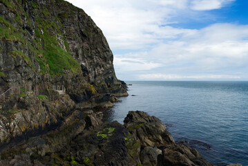 Fototapeta premium Felsen beim Klippenpfad Gobbins Cliff mit Wolken