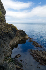Felsen beim Klippenpfad Gobbins Cliff mit Wolken und blauem Himmel