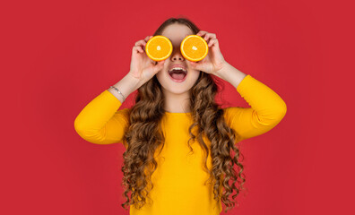 amazed teen child hold orange fruit on purple background