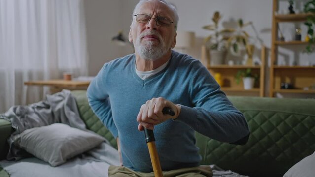 Unhappy mature man feeling bad, suffering from backache, holding his back
