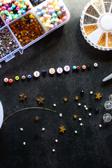Colorful beads and various jewelry making supplies on dark background. Letter beads spelling I heart DIY. Top view.