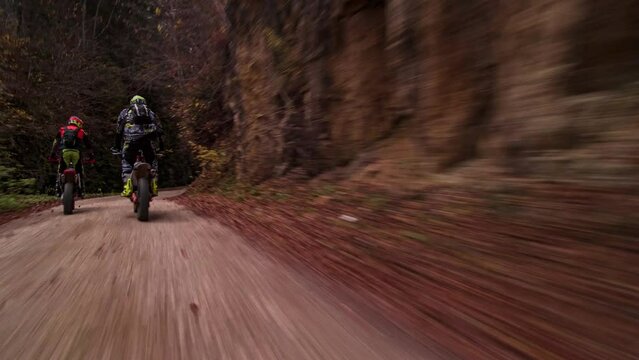 Rolling shot follow crane bikers men on motocross bikes enduro speed racing on mountain off road during fall. Concept of motorsport lifestyle