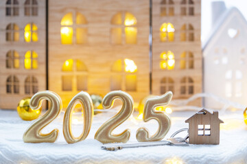 Golden figures number 2025, key and tiny home on background of cozy windows of a house with warm light with festive decor of stars,snow and garlands. Greeting card, Happy New Year, cozy home
