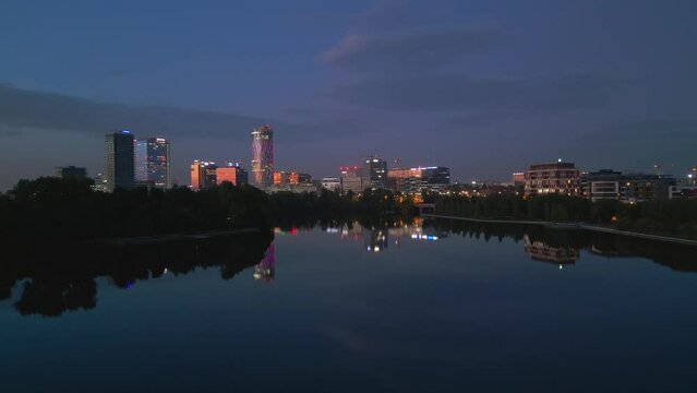 Establishing Aerial Shot Of Bucharest City Skyline And Lake Floreasca At Blue Hour