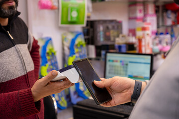 A man makes contactless payments at a bookshop or gift shop using his smartphone , seamlessly...