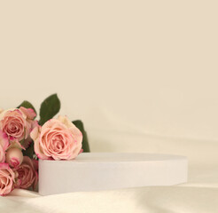 Pink rose flower bouquet on white podium and silk fabric.. Light beige background. Minimal empty display product presentation scene.