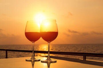 Glasses, red wine and tropical sunset with sea background, nobody.