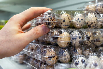 Quail eggs on the store shelf. A customer takes a packaging of quail eggs from a supermarket...