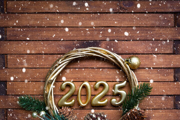 Happy New Year golden numbers 2025 on cozy festive brown wooden background with sequins, snow,...