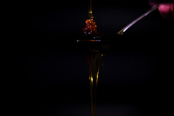 Honey dripping from spoon, isolated on black backgraund..
