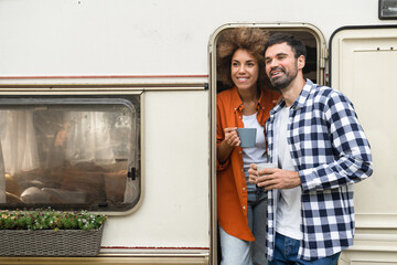 Young couple spouses mixed-race husband and wife girlfriend and boyfriend hugging having breakfast together in van trailer motor camper home, driving on road in trip voyage
