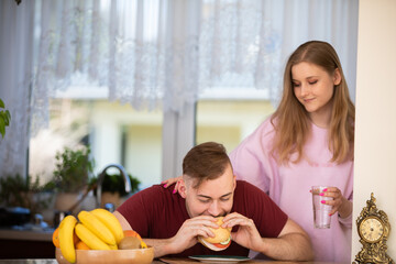 Obraz na płótnie Canvas A man sitting in the kitchen eating a sandwich for breakfast.