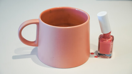 Pink color concept with pink nail polish and pink colored mug with isolated background