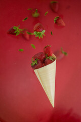 Strawberry levitating on a red background. A bowl of falling strawberries