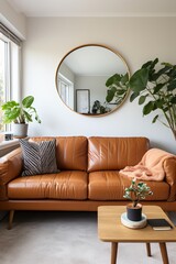 brown leather sofa in living room with round mirror and plants