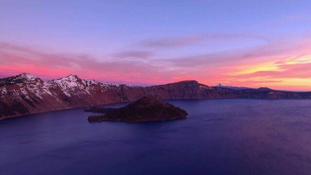 Aerial Panning Idyllic Shot Of Tranquil Mountains In Snow, Drone Flying Forward Over Crater Lake In Famous National Park During Sunset