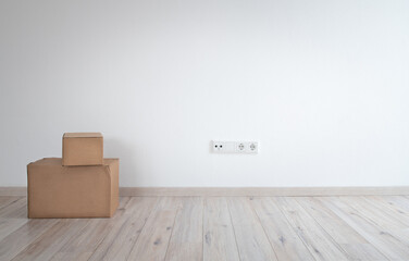 A white plastered wall in an empty room. In the foreground, the floor made of light-coloured wooden...
