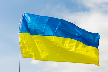 Blue and yellow flag of Ukraine, symbol of national natural resources, pride and heritage, representing sky, golden wheat fields and harvest fluttering on flagpole on sunny day.