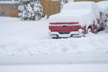 close up on truck parked on driveway covered by snow during blizzard
