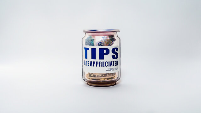 Jarro de propinas con billetes y monedas de varias denominaciones. Propinas de la industria de servicios, salario m&iacute;nimo y concepto de propina como una forma &uacute;nica y creativa de almacenar dinero