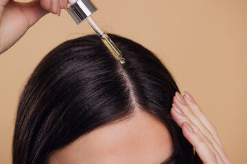 Close up view of young woman putting hair serum for alopecia and hair growth