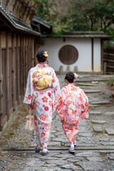 Fototapeta premium Two girls wearing Japanese traditional Kimono walking on the street. Kyoto, Japan.