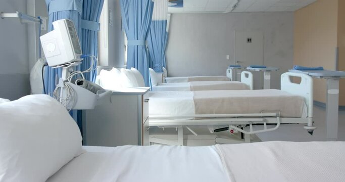Row of empty, freshly made beds and equipment in empty hospital ward, copy space, slow motion