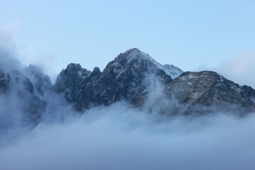 Kežmarský štít (2 556m/8 386ft a.s.l.) is a mountain in the High Tatras in Slovakia. The peaks of the mountains are shrouded in clouds in the evening in late autumn. - obrazy, fototapety, plakaty
