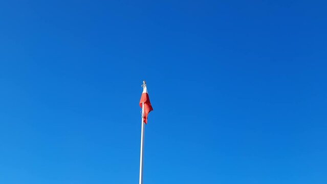 Flag of Poland flies on clear blue sky background. National holiday, independence day, constitution, elections. Concept of travel, historical sightseeing, culture.