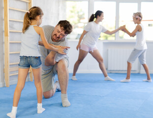 Father teaches his little daughter to use forceful techniques and grips during self-defense classes