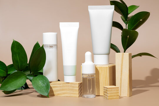 Elegant skincare products on wooden stands with greenery