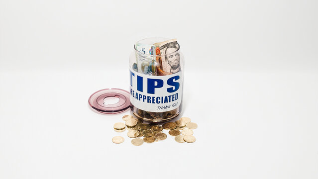 Jarro de propinas con billetes y monedas de varias denominaciones. Propinas de la industria de servicios, salario m&iacute;nimo y concepto de propina como una forma &uacute;nica y creativa de almacenar dinero