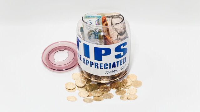 Jarro de propinas con billetes y monedas de varias denominaciones. Propinas de la industria de servicios, salario m&iacute;nimo y concepto de propina como una forma &uacute;nica y creativa de almacenar dinero