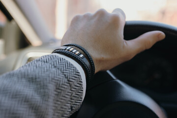 Classical male leather bracelet on a hand in the car - 705301270