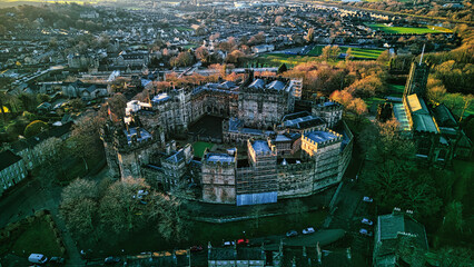 Aerial view of a historic Lancaster castle amidst a lush urban landscape at sunset.