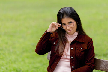 Close-up portrait of a young and beautiful woman with glasses, looking suspiciously at the camera...