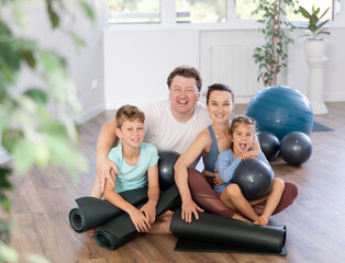 Fototapeta na wymiar Happy portrait of family of four with mats and soft balls going to practicing yoga at gym