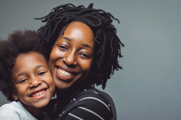 Black parent and child portrait, cuddling and smiling. Studio shot on gray background.