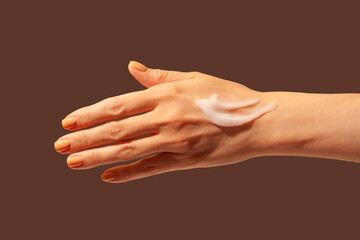 Cosmetic smudge cream texture on woman hand brown background