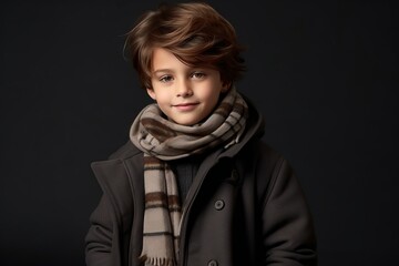 portrait of a cute little boy in a coat and scarf on a dark background