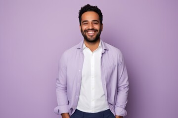 Portrait of a handsome young arabic man looking at camera and smiling while standing against purple background - obrazy, fototapety, plakaty