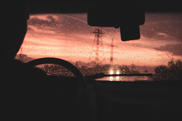 view from a car on the highway in bad weather conditions, rain and fog, at a beautiful red sunset