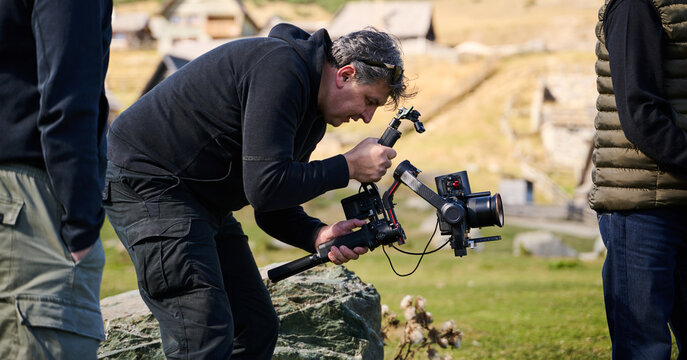 A skilled videographer, equipped with professional gear, captures the essence of nature's beauty, expertly documenting the scenic landscape in a cinematic masterpiece that reflects the seamless blend