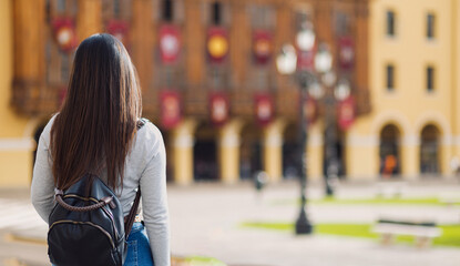Young woman with her back turned, enjoying the views of squares and streets in a tourist city