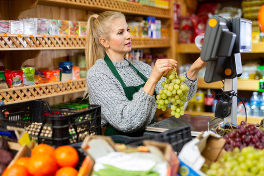 Portrait of a positive female salesperson at the checkout counter at a grocery supermarket